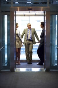 Successful business people standing in office elevator and talking with each other